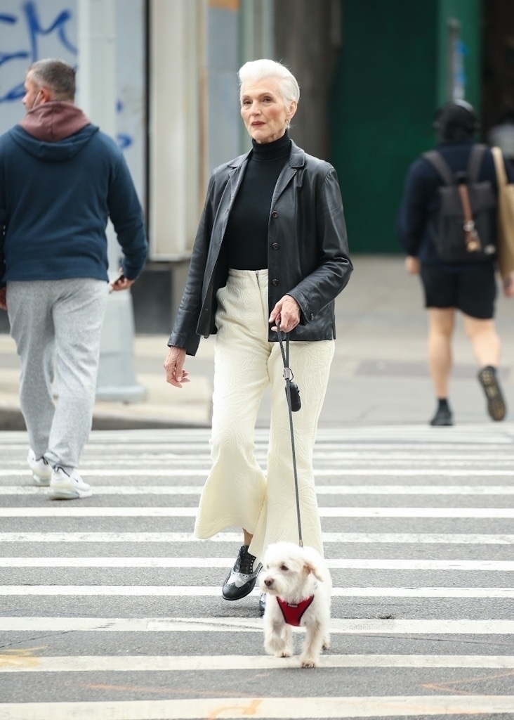 Maye Musk, klädd i en svart skinnkappa med smarta byxor, promenerar med sin hund i New York